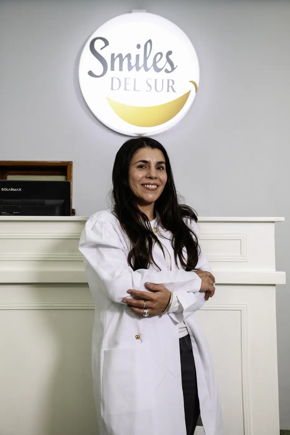 Odontóloga de Smiles del Sur en la recepción, junto al logo del consultorio