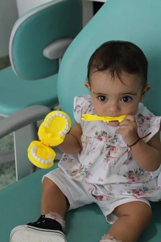 Bebé jugando con un modelo de dientes en el sillón odontológico